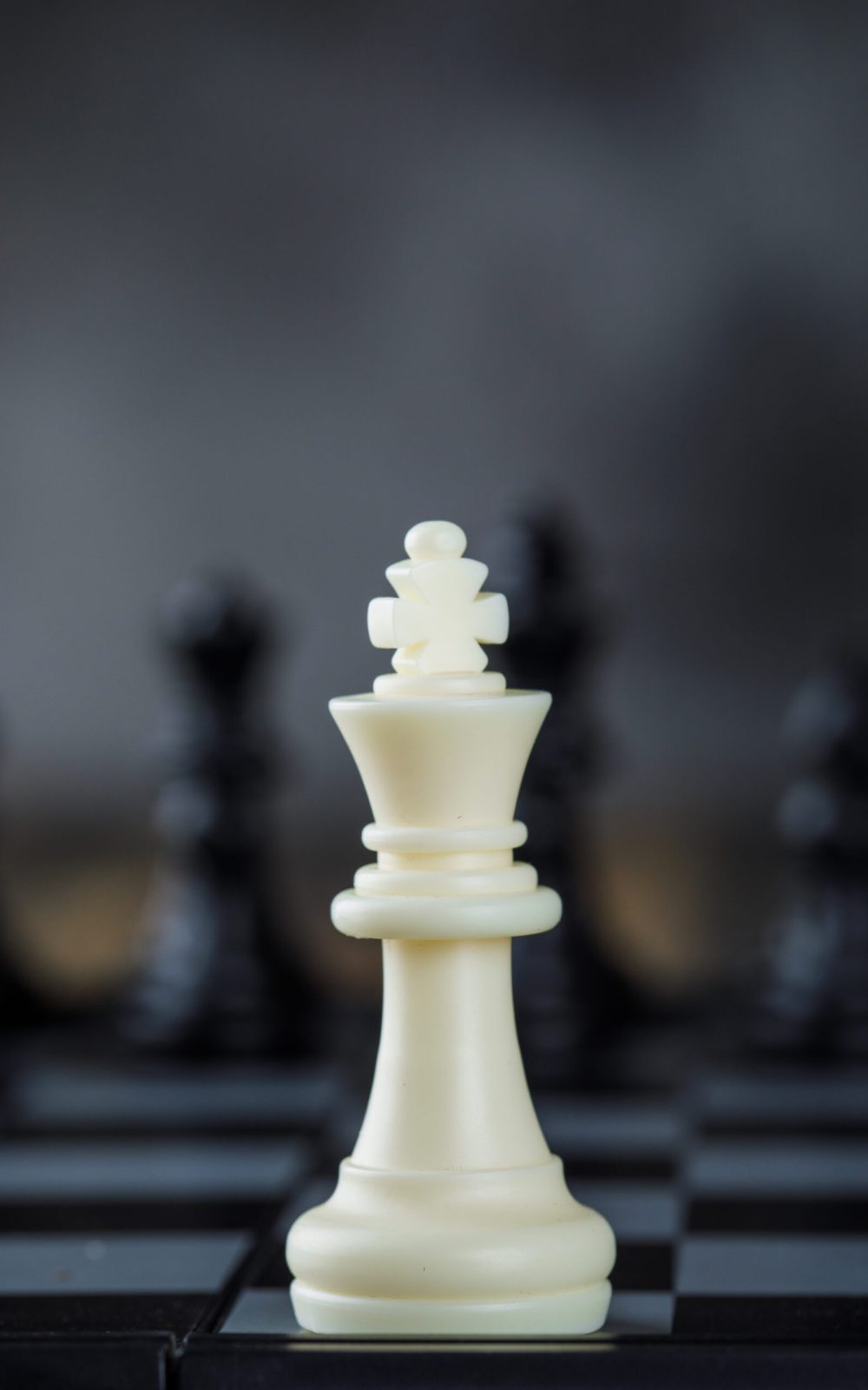 Business strategy concept with figures on chessboard on blurred and wooden background close-up.
